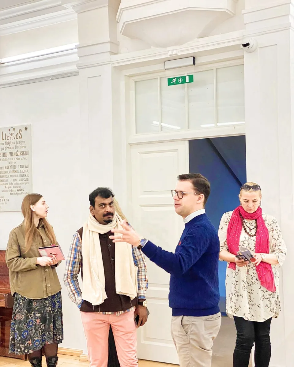 Ramesh Terdal listening as a host speaks with visiting artists in a white hall