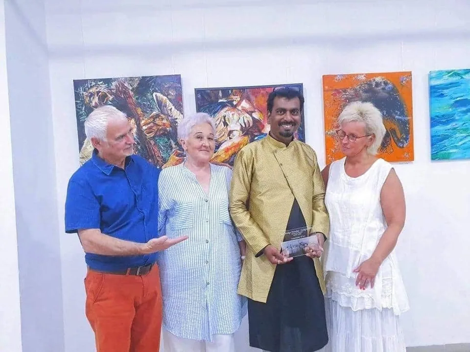 Ramesh Terdal holding the Ambassador of Art recognition with fellow artists in a gallery