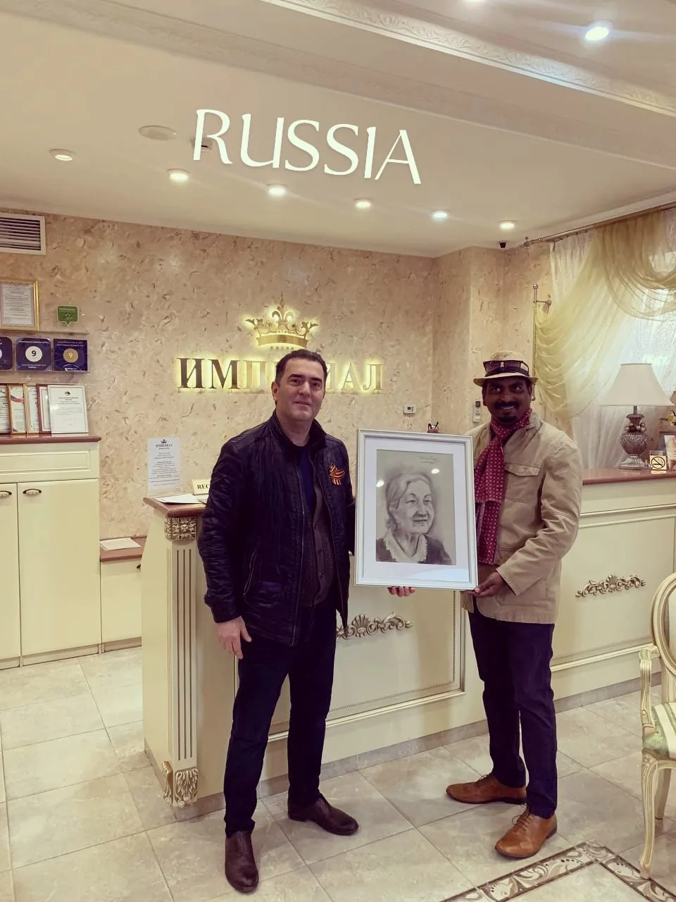 Ramesh Terdal presenting a framed charcoal portrait in Russia